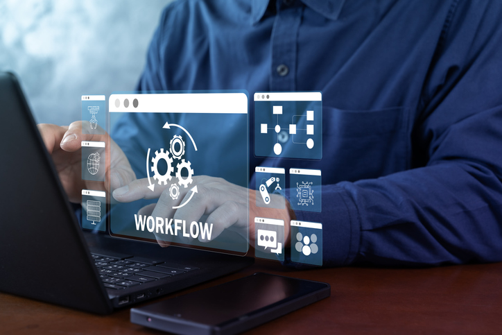 A person typing in a laptop. Workflow imagery is showing